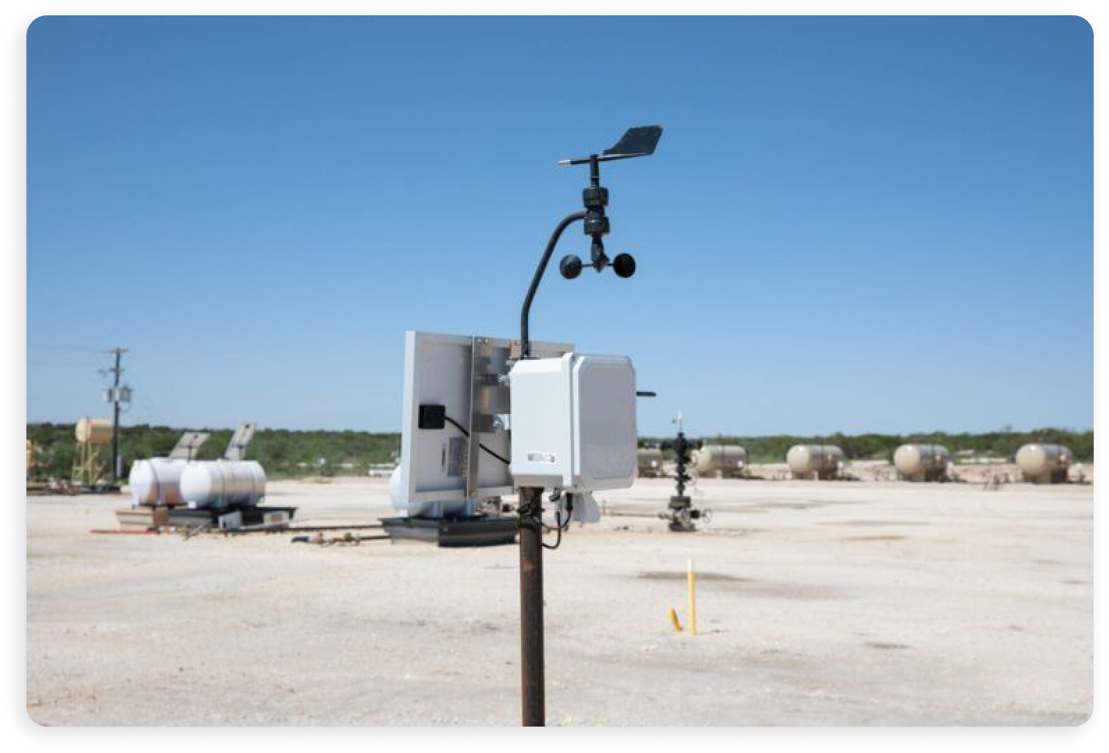 The image depicts an outdoors industrial facility featuring tanks, solar panels, and an IIoT monitoring device.